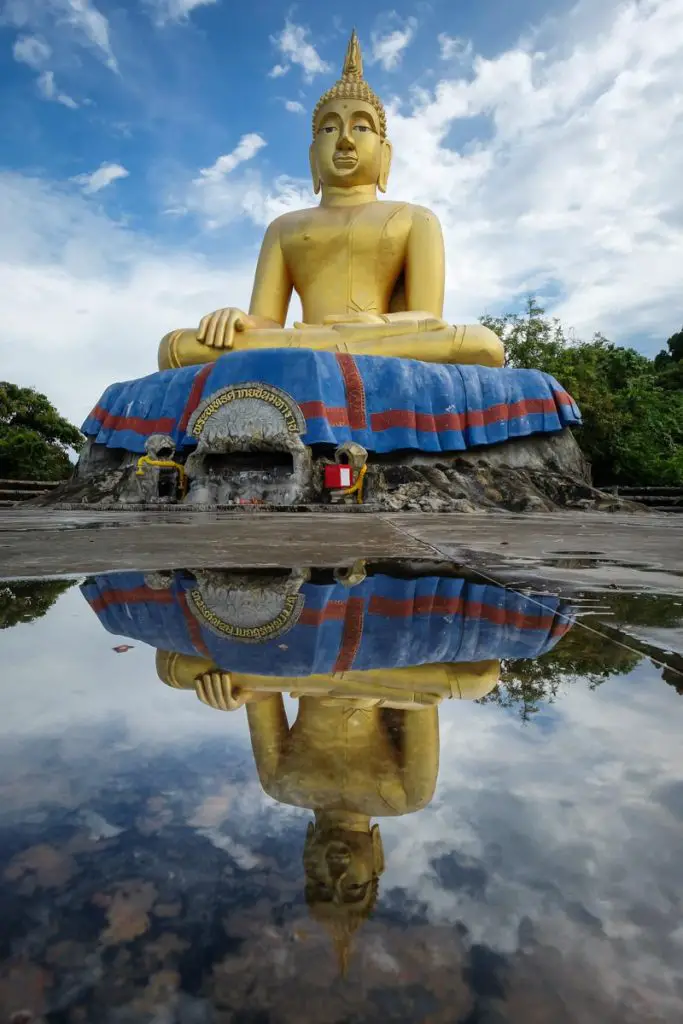 Golden Buddha statue reflected in a pool in Thailand.